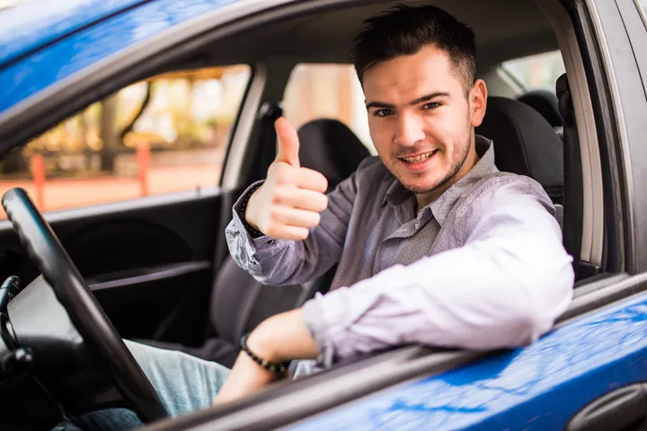 Taxista colombiano sonriendo dentro de su vehículo